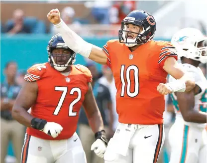  ?? GETTY IMAGES (ABOVE), AP ?? Mitch Trubisky (above) celebrates after throwing a touchdown pass to Allen Robinson in the third quarter Sunday against the Dolphins, but safety T.J. McDonald’s intercepti­on (below) in the fourth came on a throw he’d like to have back.
