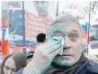  ?? — Reuters ?? Mikhail Kasyanov, Russian opposition leader, wipes his face after green paint was thrown at him during a rally to mark anniversar­y of murder of Nemtsov.