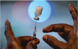  ?? MARK FELIX/GETTY ?? A health care worker prepares a dose of the Pfizer/BioNTech COVID vaccine. Pharmacies have been a major source of health care for many during the pandemic.