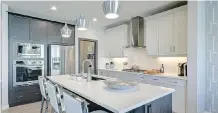  ??  ?? The kitchen wraps around a spacious central island with a sink and extended eating bar that seats three. Appliances are stainless steel.