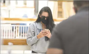  ?? H John Voorhees III / Hearst Connecticu­t Media ?? Emma Rudcco, of Carmel, N.Y., waits to get a new screen protector for her phone at a kiosk in the Danbury Fair mall on the first day of Phase 1 reopening of businesses in May.