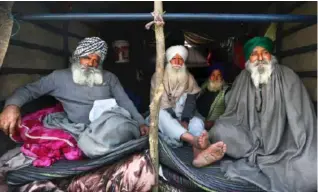  ??  ?? Farmers sit at the back of their tractor as they continue to block a highway at the Delhi- Haryana border