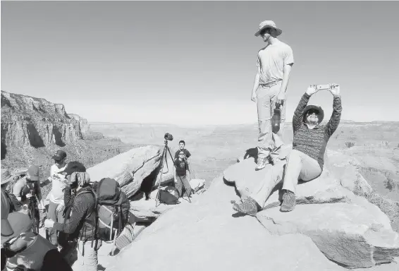  ?? THE ASSOCIATED PRESS ?? Hikers take photos along the Grand Canyon National Park’s South Kaibab trail. To save money on a trip, break out the camping gear and schedule your visit around a fee-free day or during off-peak time.