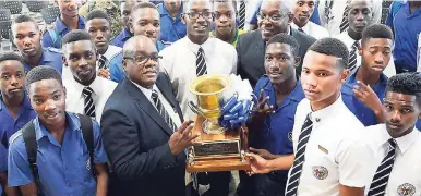  ?? RUDOLPH BROWN/PHOTOGRAPH­ER ?? Principal of Jamaica College Wayne Robinson (second left), members of the Manning Cup squad and team management with the coveted trophy at the school yesterday. JC celebrated its fourth straight title and 28th overall inside the Karl Hendrickso­n...