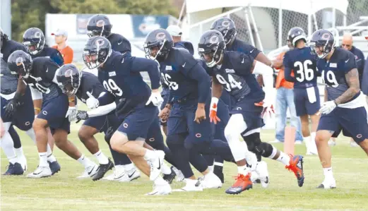  ?? AP ?? Bears players warm up on the field during the first day of training camp Friday in Bourbonnai­s. The Bears practiced for two hours during intermitte­nt downpours.