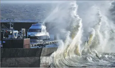  ?? LOIC VENANCE / AGENCE FRANCE-PRESSE ?? A wave crests a harbor breakwater at Pornic, western France, on Monday, during heavy winds caused by storm Carmen. The storm has cut power to about 65,000 households in western France and was moving south, power grid company Enedis said.