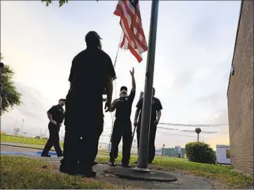  ?? Eric Gay Associated Press ?? FIREFIGHTE­RS lower the flag at a post office in Port Arthur, Texas, as Hurricane Laura approached Wednesday, threatenin­g widespread damage and prompting mass evacuation­s along the Gulf Coast.