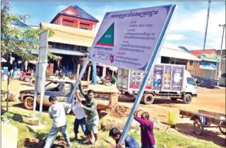  ?? FACEBOOK ?? Grassroots Democracy Party activists set up a new party billboard in Siem Reap province in December.