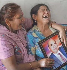  ?? Photo: AFP ?? Gyan Kaur holds a photograph of her husband Balwant Rai after hearing confirmati­on of his death.