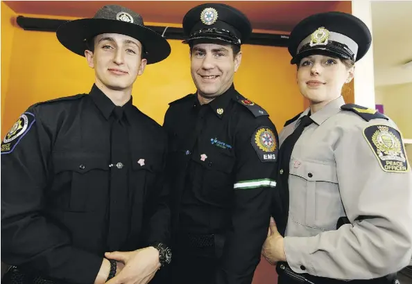  ?? IAN KUCERAK ?? From left, commercial vehicle enforcemen­t officer Aaron Smith, Alberta Health System EMS public education officer Alex Campbell and University of Alberta Protective Services peace officer Stephanie Hartwig model a new anti-bullying pin for law...