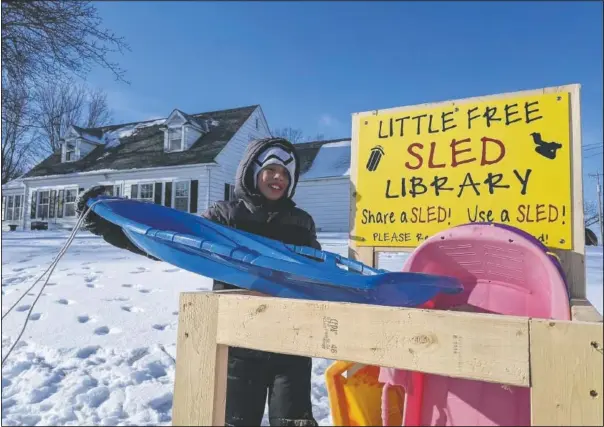  ??  ?? Jace Prohaska, 9, of Kansas City, Mo., borrows a sled from the Little Free Sled Library in Ventura, Iowa. He and his brother spent hours at the sledding hill at Lynne Lorenzen Park this past weekend. (Globe-Gazette/Ashley Stewart)
