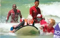  ??  ?? Pamela Hanford, 75, is helped by a team of coaches and volunteers to surf at an adaptive surfing event at Muizenberg beach in Cape Town, South Africa.