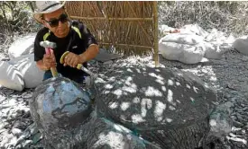  ?? —PHOTOS BY EV ESPIRITU ?? Korean sculptor Bong Kim, who built the “Bahay na Bato” in the coastal town of Luna in La Union province, starts shaping a boulder into a piece of art. Photo below shows one of his creations, a headless woman, backdroppe­d by a wall adorned by images of...