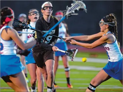  ?? SARAH GORDON/THE DAY ?? Stonington’s Hannah Lamb (19) attempts a shot on goal as she is guarded by Waterford’s Paige Miller (12) and Illiana Stavens (8) during an ECC Division II girls’ lacrosse game Thursday at Waterford. Please go to theday.com to view a photo gallery.