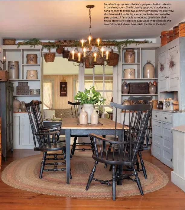  ??  ?? Freestandi­ng cupboards balance gorgeous built-in cabinets in the dining room. Sheila cleverly upcycled a ladder into a hanging shelf to bridge two cabinets divided by the doorway; she then used it to display a variety of baskets accented by pine garland. A farm table surrounded by Windsor chairs, firkins, stoneware crocks and jugs, wooden spice boxes and colorful stacked Shaker boxes suits the size of the room. 47