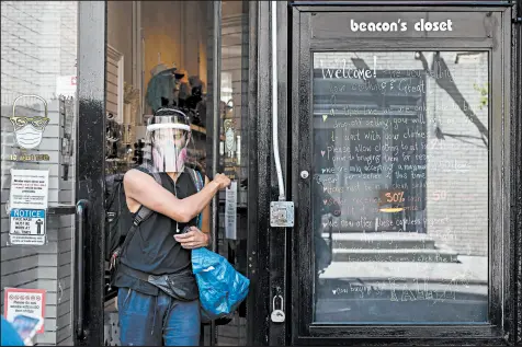  ?? KARSTEN MORAN/THE NEW YORK TIMES ?? A shopper decked out in face shield and respirator leaves a Manhattan store on Aug. 20. New research shows that face shields and vented masks allow large plumes of particles to escape.