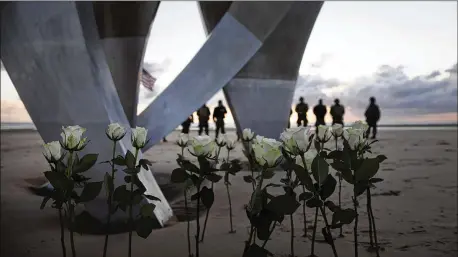  ?? PHOTOS BY VIRGINIA ?? Men in vintage U.S. WWII uniforms stand behind flowers left at Les Braves monument after a D-Day 76th anniversar­y ceremony Saturday in Saint-Laurentsur-Mer, France.
Charles Norman Shay, a D-Day WWII veteran from Maine, salutes Saturday after laying a wreath during a D-Day ceremony at the Normandy American Cemetery in Colleville­sur-Mer, France. Due to coronaviru­s measures, many ceremonies and memorials were canceled in the region.