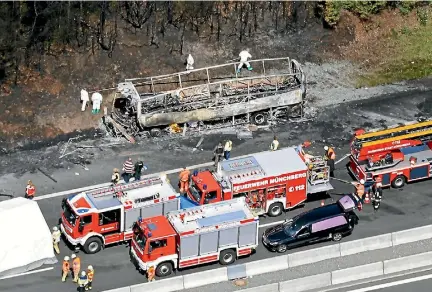  ?? PHOTO: GETTY IMAGES ?? Fire and rescue workers stand near the burned-out wreckage of a passenger bus on the A9 highway in northern Bavaria.