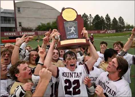  ?? HELEN H. RICHARDSON — THE DENVER POST ?? Cheyenne Mountain’s Logan Mika holds the Class 4A lacrosse state championsh­ip trophy as he and his teammates celebrate their win over Erie at Peter Barton Stadium on the DU campus on Monday night.