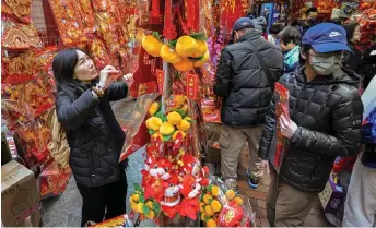  ?? — AFP photo ?? People shop for Lunar New Year decoration­s in Hong Kong, for the upcoming Year of the Dragon. Hong Kong is to introduce a new security law to expand on legislatio­n imposed in June 2020 to silence dissent.