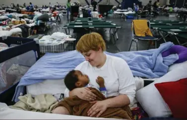  ?? MICHAEL CIAGLO/ THE ASSOCIATED PRESS ?? Shiann Barker holds her 1-year-old nephew between cots at the George R. Brown Convention Center, where nearly 10,000 people are taking shelter after tropical storm Harvey.