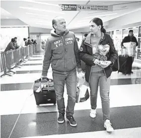 ?? MARY ALTAFFER/AP ?? Mohammed Hafar, left, helps his daughter Jana with her luggage as they leave JFK Airport in New York on Dec. 3. Jana was forced by the travel ban to stay in Syria for months.