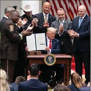  ?? (The New York Times/Doug Mills) ?? As law enforcemen­t officials gather around him Tuesday in the White House Rose Garden, President Donald Trump displays his signed executive order on safe policing for safe communitie­s. More photos at arkansason­line.com/617police/.