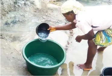  ??  ?? A resident of Madalla village scooping water from a stream