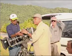  ?? Mikki Ansin / Getty Images ?? Director Ismail Merchant, center, on the set of "Mystic Masseur" stands at the camera in Port of Spain, Trinidad, while director James Ivory, right, assists him in 2001.