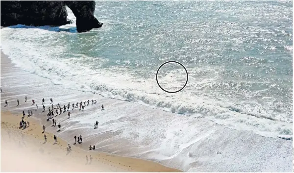  ??  ?? Beachgoers run to form a human chain to reach a man struggling against fierce waves at Durdle Door in Dorset