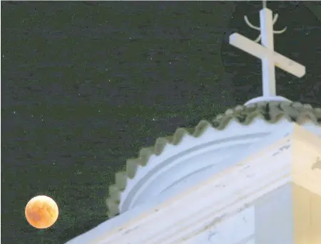  ??  ?? A full moon rises over a Christian Orthodox church in Ergates village near Nicosia, Cyprus, during the complete lunar eclipse. It’s called a “blood moon” because it turns a deep red. North America missed out on Friday’s lunar eclipse.