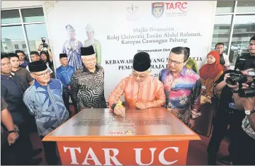  ?? — Bernama photo ?? Tengku Abdullah (centre) signs a plaque to officiate the launch of TARC flanked by Najib (second left) and Liow.