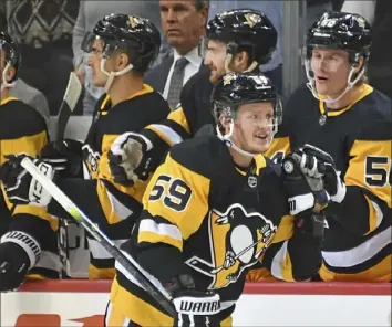  ?? Peter Diana/Post-Gazette ?? HIGH FIVE Jake Guentzel receives congratula­tions Wednesday night after scoring his fifth goal of the season in the second period of the Penguins 3-2 overtime victory against the Colorado Avalanche at PPG Paints Arena.