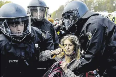  ?? FILIP SINGER / EFE ?? Policías antidistur­bios desalojan a una manifestan­te en una protesta contra el Gobierno, ayer en Berlín.