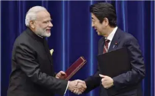  ?? — AP ?? TOKYO: India’s Prime Minister Narendra Modi (left) and Japan’s Prime Minister Shinzo Abe shake hands after signing a joint statement at Abe’s official residence yesterday.