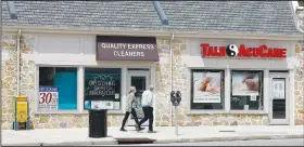  ?? (AP/Matt Slocum) ?? A couple walks past a row of closed businesses Wednesday in Upper Darby, Pa.