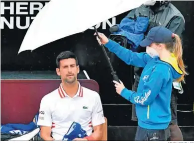  ?? ETTORE FERRARI / EFE ?? Djokovic se protege de la lluvia bajo un paraguas.