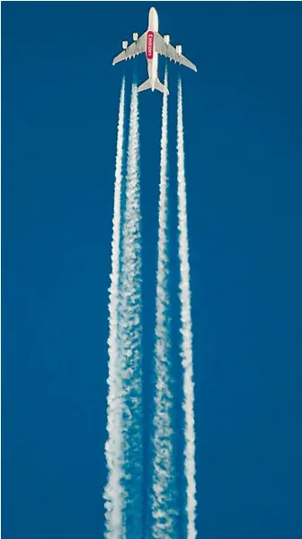  ?? Photos: Getty Images, AFP ?? Below: A mural on a wall near the Scottish Events Centre, which has hosted the COP26 UN Climate Summit this week.
Above: Jet contrails can become diffuse cirrus clouds that reflect terrestria­l radiation, increasing global warming (above); passengers at Lisbon Humberto Delgado Internatio­nal Airport (below).