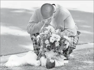  ?? CHRIS O’MEARA / ASSOCIATED PRESS ?? Jeremy Bush places flowers and a stuffed animal Saturday at a makeshift memorial in front of a home where a sinkhole opened up underneath a bedroom late Thursday evening and swallowed his brother Jeffrey in Seffner, Fla.