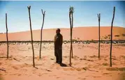  ?? Josh Haner / New York Times ?? Guo Kaiming stands between trees he planted to help hold back the sand in the Tengger Desert in China. Guo, a farmer, also manages a sand sculpture park.