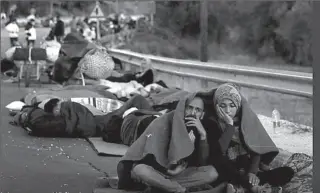  ?? LESBOS, GREECE
-REUTERS ?? Refugees take rest on road after fire guts their shelters on the island of Lesbos in Greece.