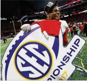  ?? CURTIS COMPTON / CCOMPTON@AJC.COM ?? Former UGA linebacker Lorenzo Carter takes home a sign after winning the SEC Championsh­ip game against Auburn last season.