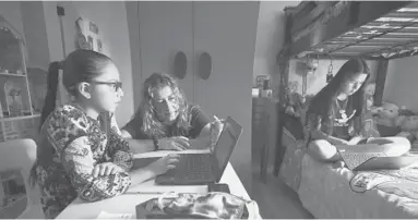  ?? ALSEIB/LOSANGELES­TIMES ?? Sofia Quezada assists her daughters Priscilla, left, and Paulette Guerrero with virtual class from their Los Angeles home. Tech issues on the first day of class drove 9-year-old Priscilla to tears.