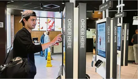  ??  ?? Catching up on innovation: A customer ordering food at a self-service kiosk in a McDonald’s restaurant in Chicago. — AP