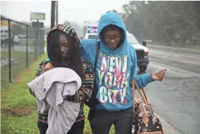  ?? JOE RAEDLE/GETTY IMAGES ?? Naiya Willis, left, and Candice Willis make their way to an evacuation bus after they left their home as the remnants of Hurricane Florence passed through the area Sunday in Fayettevil­le, N.C.