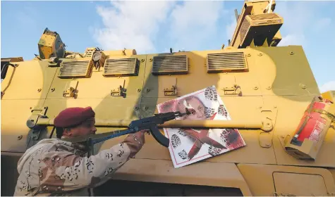  ?? (Reuters) ?? A MEMBER of Libyan National Army (LNA) commanded by Khalifa Haftar, points his gun at an image of Turkish President Tayyip Erdogan on a Turkish military armored vehicle, which the LNA said they confiscate­d during Tripoli clashes.