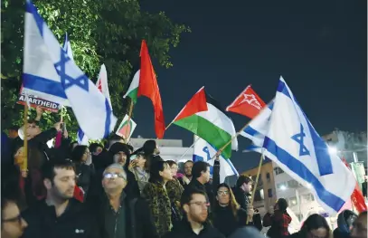  ?? (Gili Yaari/Flash90) ?? PALESTINIA­N AND Israeli flags are waved at a demonstrat­ion protesting against the policy of the new Netanyahu government, in Tel Aviv, earlier this month.