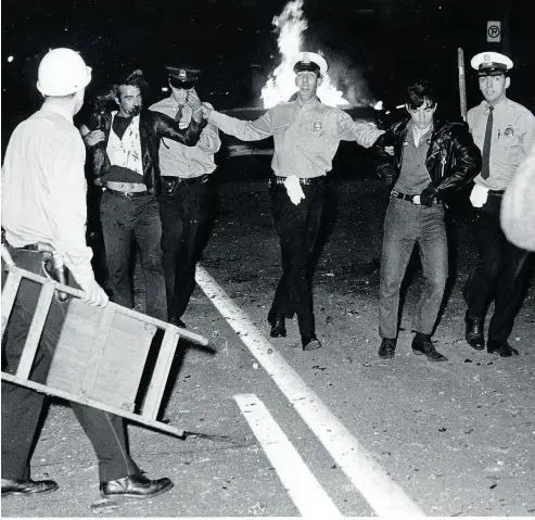  ?? MONTREAL STAR FILES ?? Two demonstrat­ors are taken to a police van as a fire burns near the St-Jean-Baptiste parade in Montreal in 1968.