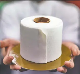  ?? MOHD RASFAN/AFP VIA GETTY IMAGES ?? Chef Gabriel Pang Yue Ken of Kuala Lumpur holds a cake resembling a roll of toilet paper, a wink at panic buying around the world when the coronaviru­s pandemic hit.