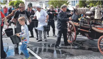  ?? FOTO: ALOIS GROSS ?? Wie anno dazumal wurde der Wassertank des historisch­en Spritzwage­ns – 1880 – bei der Vorführung durch die Feuerwehr Aixheim mit einer Eimerkette laufend gefüllt.